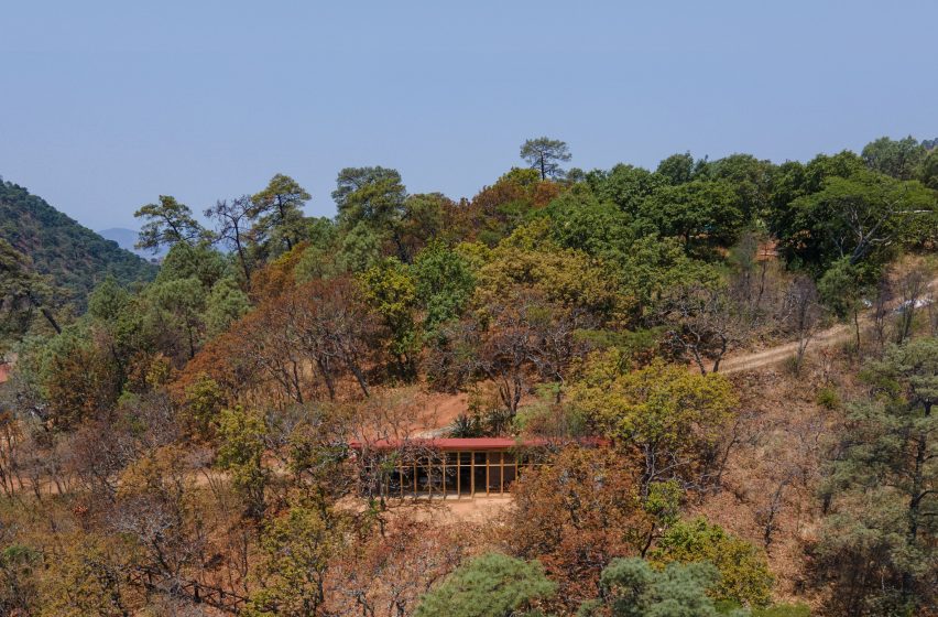 Wooden one-storey shed-like home on a sandy hill in Mexico with trees