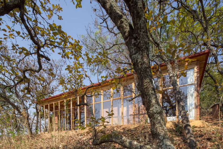 Wooden one-storey shed-like home on a sandy hill in Mexico with trees