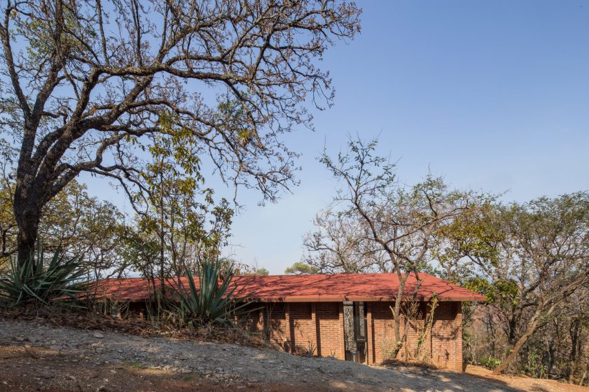 Wooden one-storey shed-like home on a sandy hill in Mexico with trees