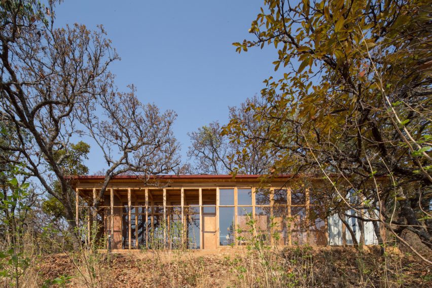 Wooden one-storey shed-like home on a sandy hill in Mexico with trees