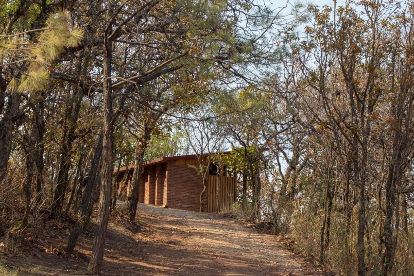 Wooden one-storey shed-like home on a sandy hill in Mexico with trees