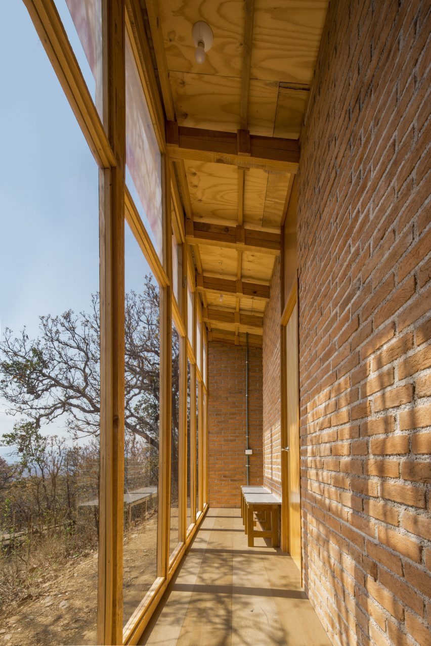 Narrow corridor with a brick wall and floor-t0-ceiling windows overlooking a sandy hillside