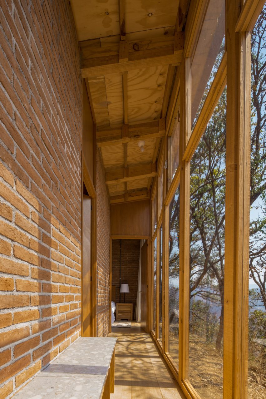 Narrow corridor in a brick home with wodden-framed windows and bench seating