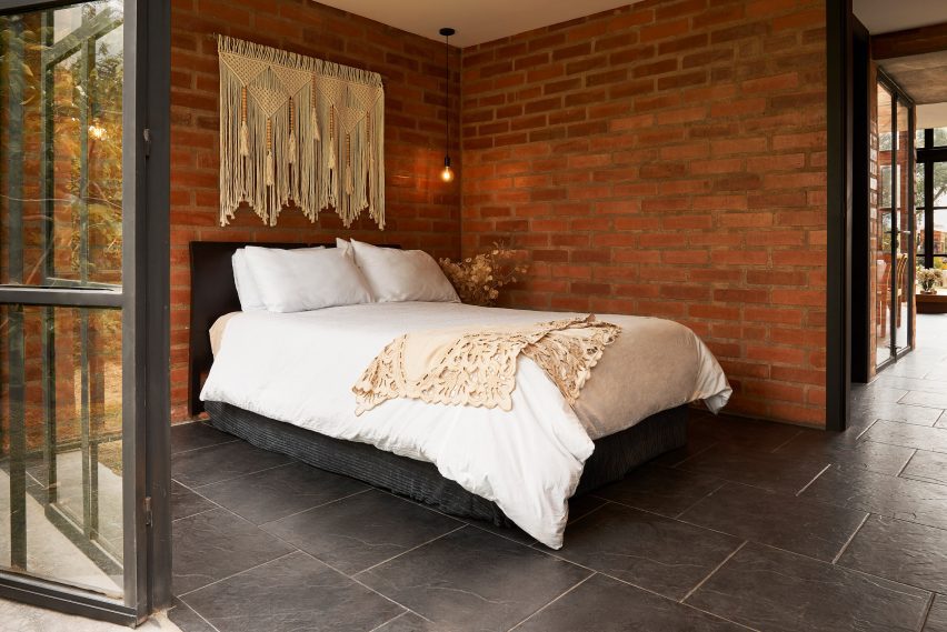 Bedroom with brick walls, a bed with white bedding and folding glass doors