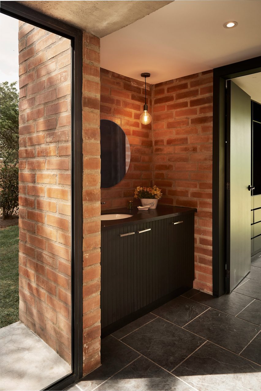 Black bathroom vanity unit in a room with brick walls