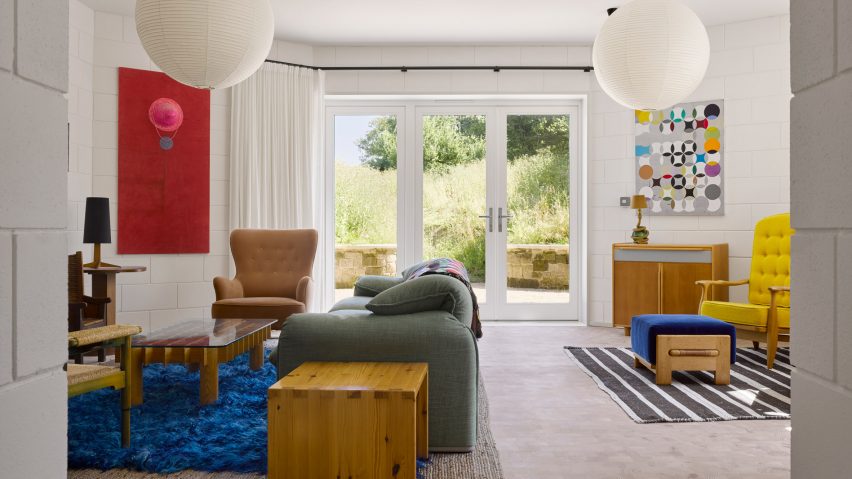 Living room with French doors, blue rug, yellow armchair and red wall hanging