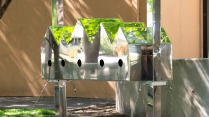A birdhouse with a series of pitched roofs and reflective surfaces