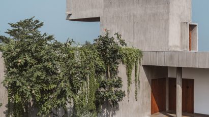 Entrance to the concrete Enclosure house by Design Ni Dukan with concrete canopy and grass lawn