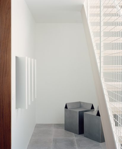 Boxy aluminium corner stools tucked under staircase