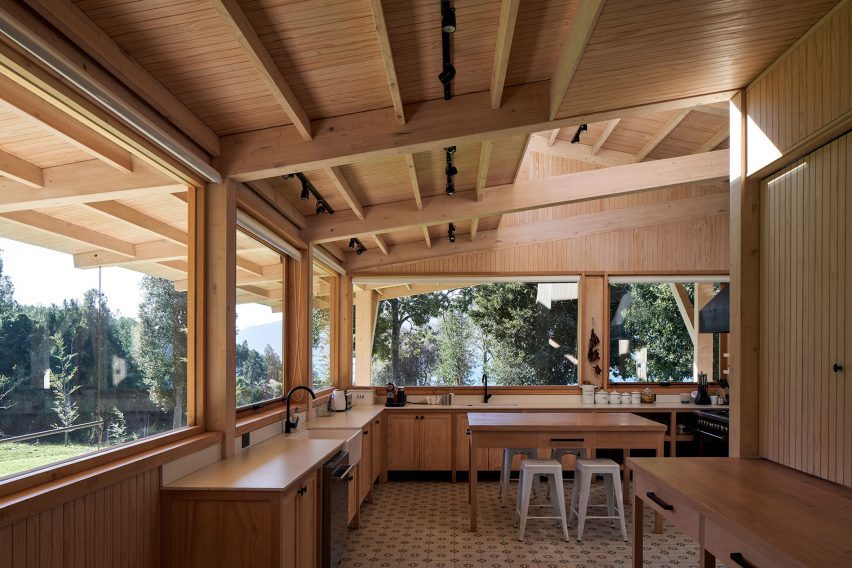A kitchen in a timber structure with wooden units and large windows