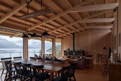A living room in a timber-clad room with a pitched roof and grey sofas