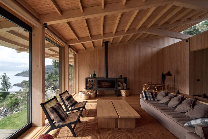 Open-plan living room with a grey sofa, black fireplace and lounge seats in a timber room