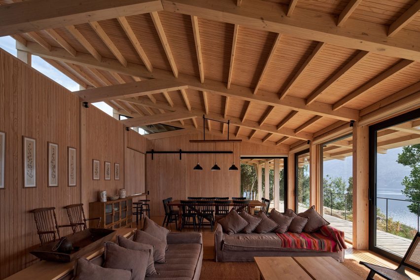 A living room in a timber-clad room with a pitched roof and grey sofas