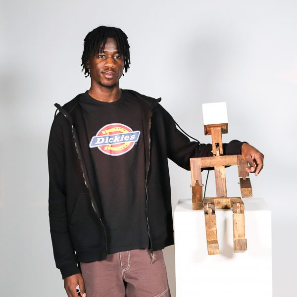 Student posing with humanoid lamp design on grey background