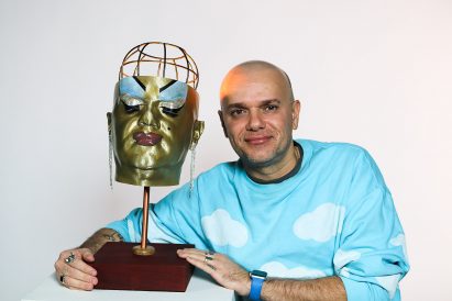 Student posing with bust-like lamp design on grey background