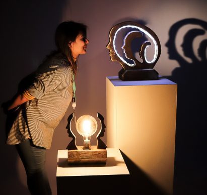 Student posing with lamps in front of grey background