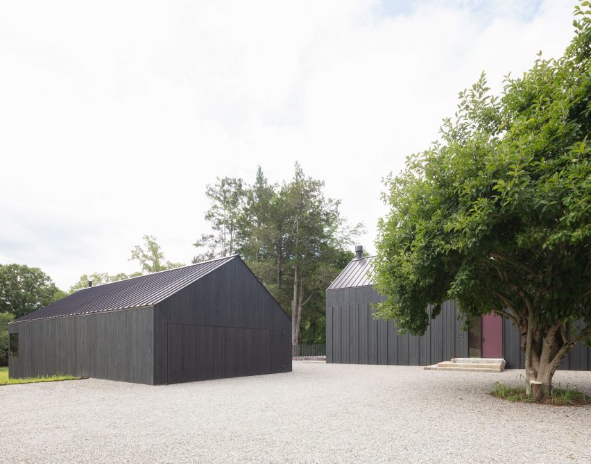 Black timber-clad structures on gravel ground
