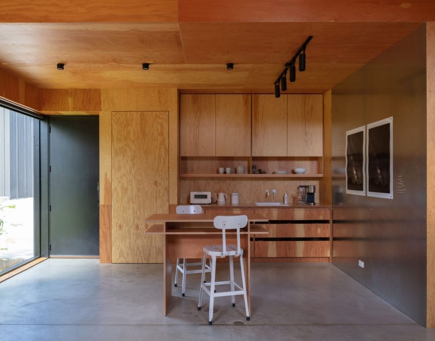 Timber-clad kitchen interior with concrete floors and wooden storage