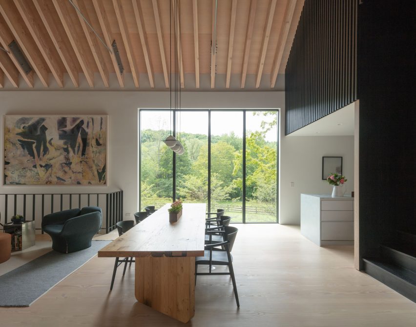 Open-plan dining and living space with timber floors, tall windows and exposed timber roof structure