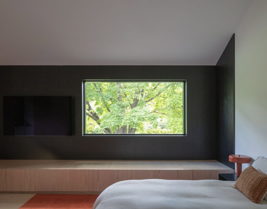 Bedroom with a dark blue accent wall at the New York farmhouse by Worrell Yeung