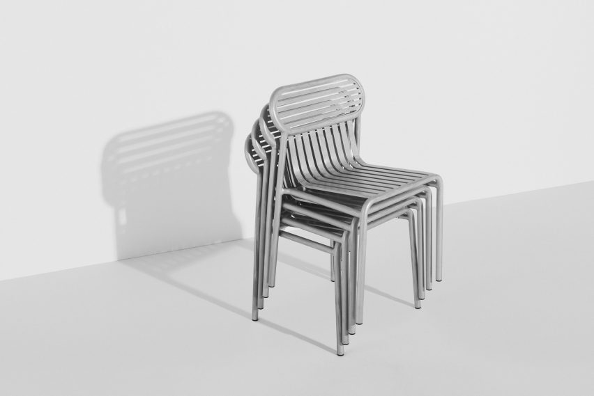 Shiny metallic chairs stacked up in white room