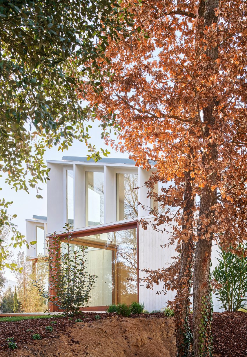 A cluster of mono-pitched square structures comprising House 016 by Arquitecturia in a wooded garden