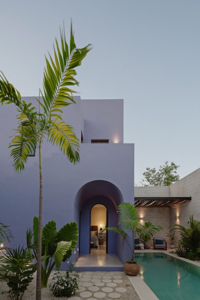 Exterior of a purple two-storey building with an arch entryway and swimming pool