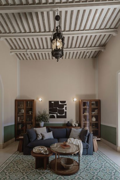Interior of a living room with mosaic floor tiles, exposed ceiling joists and a blue sofa