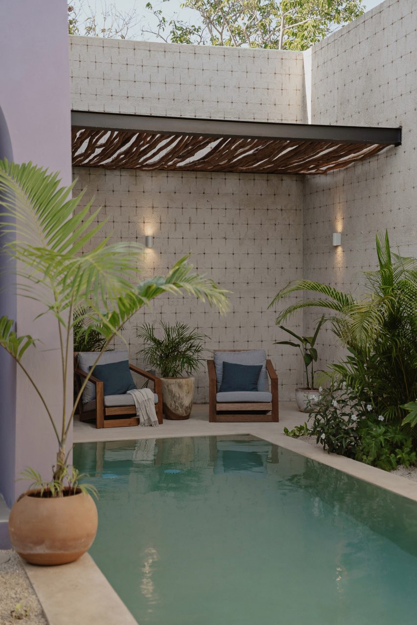 A swimming pool with a terrace and lounge chairs with wood cover overhead