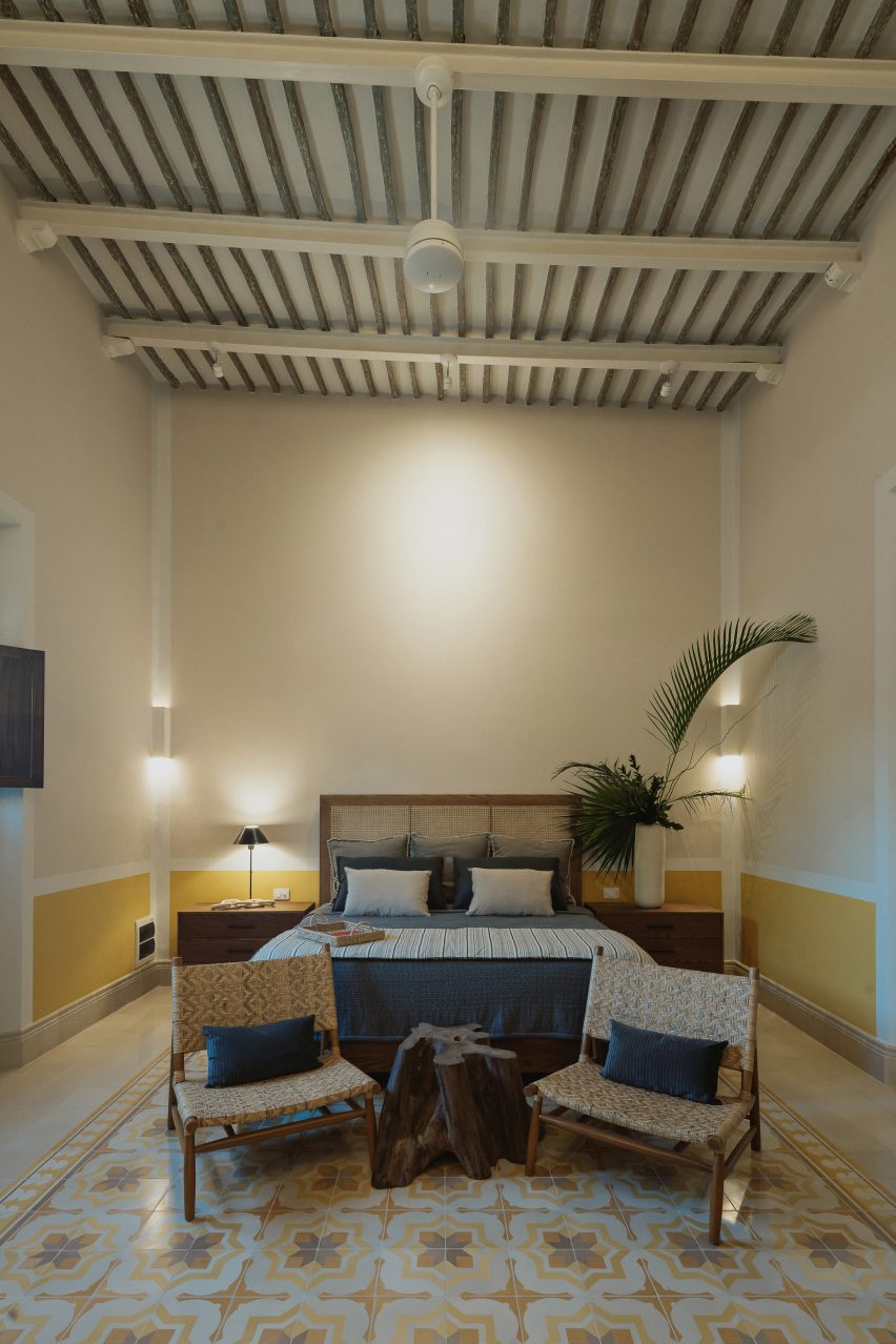 A bedroom with yellow lower walls and a bed with navy bedding