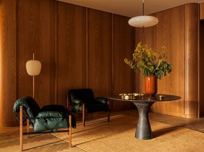 Wood-panelled seating area with two slingback chairs and a marble table