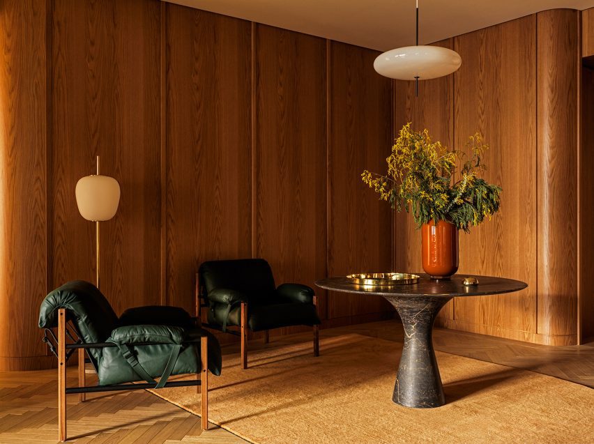 Wood-panelled seating area with two slingback chairs and a marble table