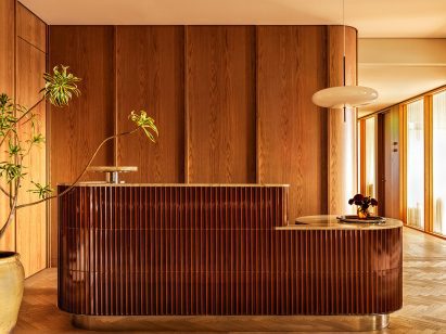 Reception desk wrapped in glossy oxblood-coloured tiles
