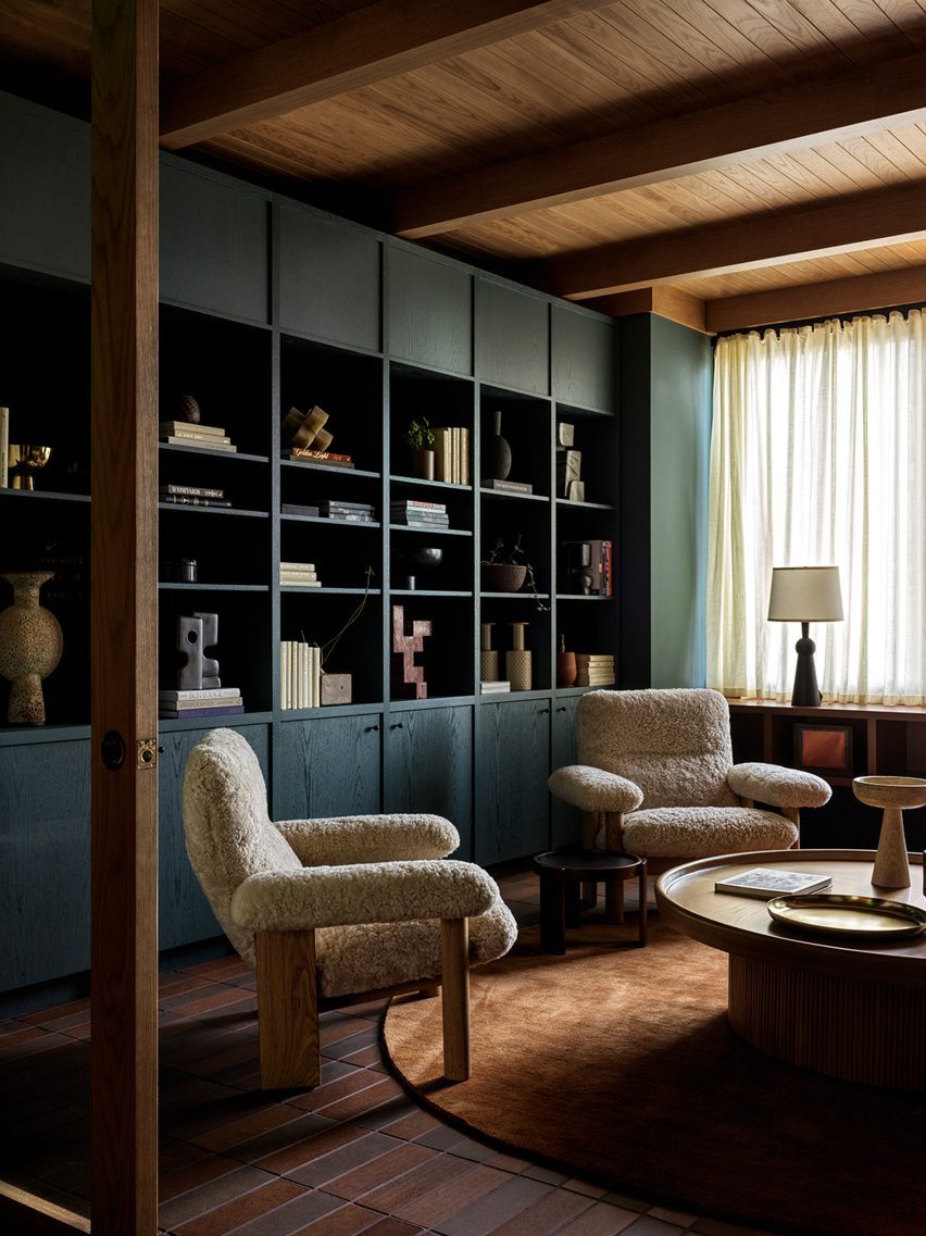 Lounge area with teal-coloured bookshelves, two armchairs and a coffee table