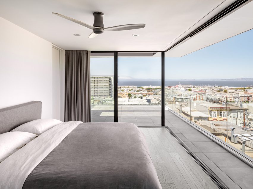 Bedroom with white walls, grey double bed and corner window
