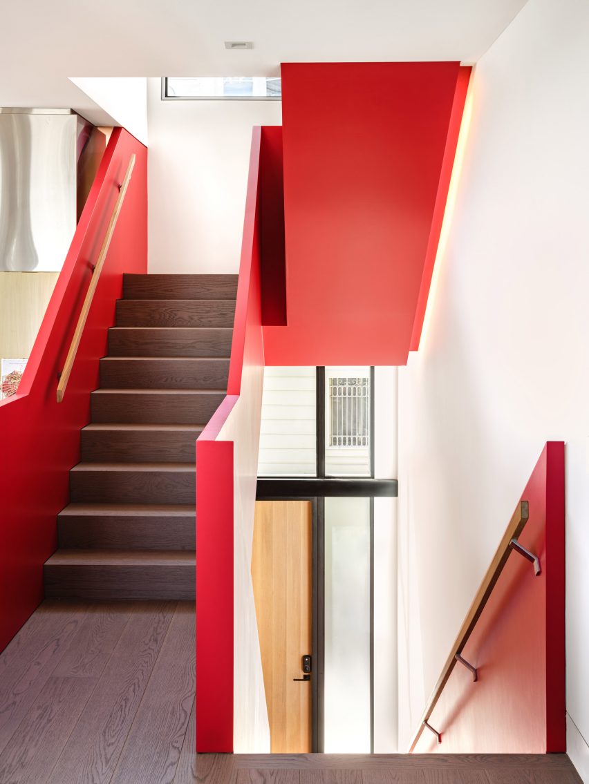 Staircase with dark wood stairs and red balustrades