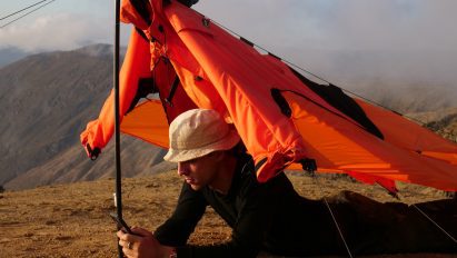 Photo of Pavel Hedström lying under the Fog-X jacket expanded into a shelter shape