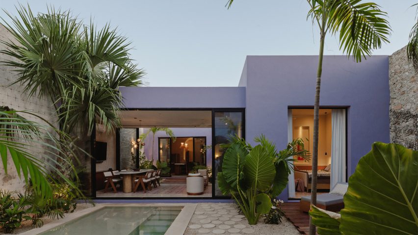 Purple rectangular one-storey building with a swimming pool and palm trees