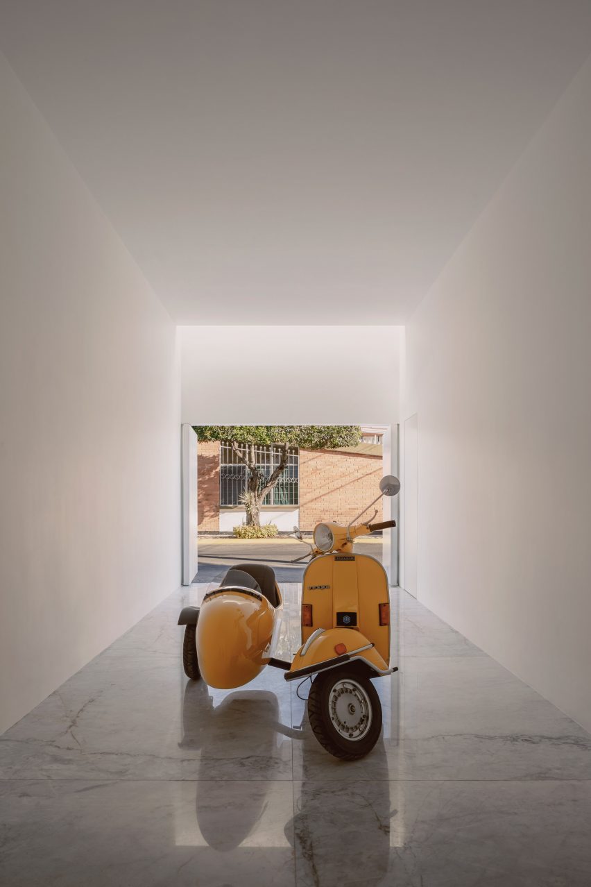 A white square garage with polished concrete floors and a yellow Vespa
