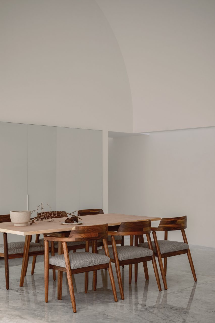 A white room with a wooden dining table and chairs