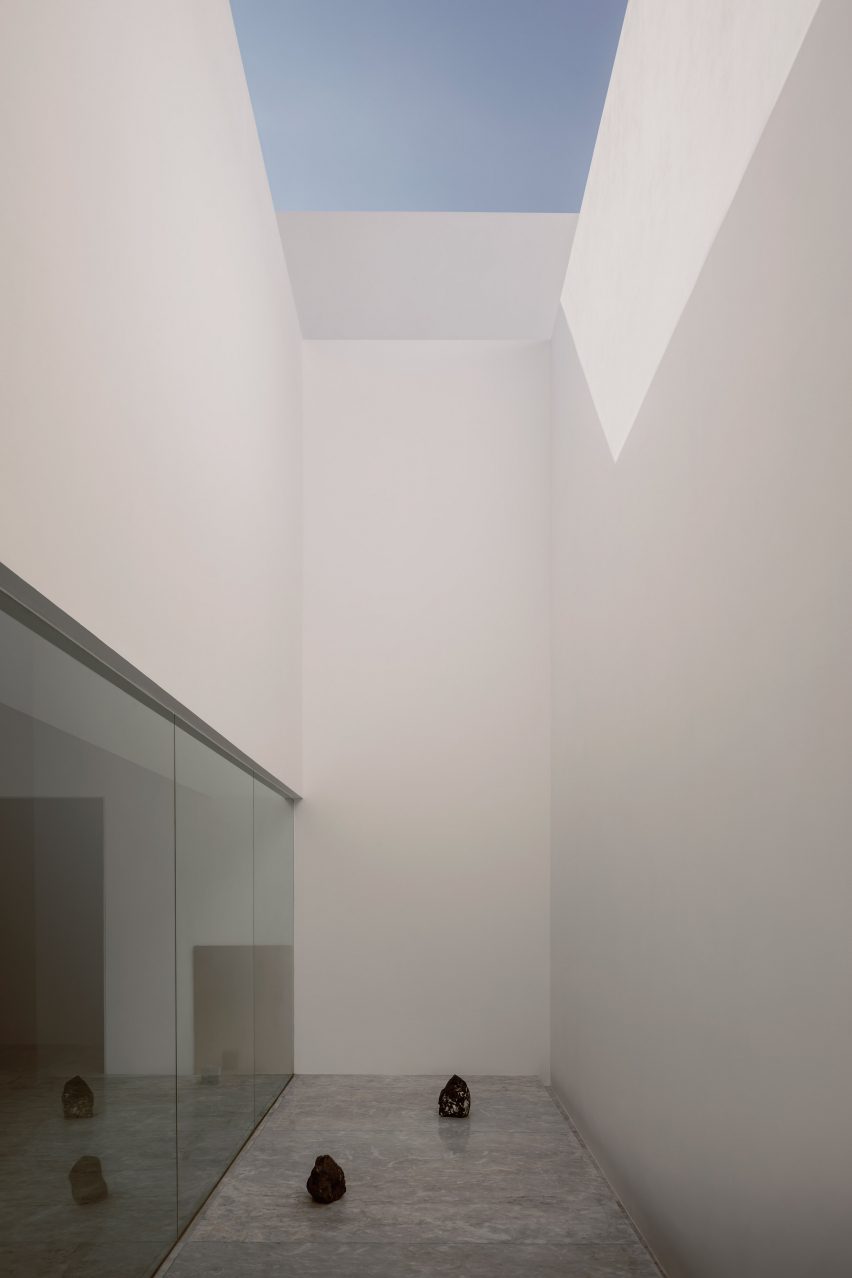 A narrow courtyard with tall white walls and glass doors