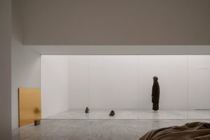 A white bedroom with sliding glass doors opening onto a white courtyard