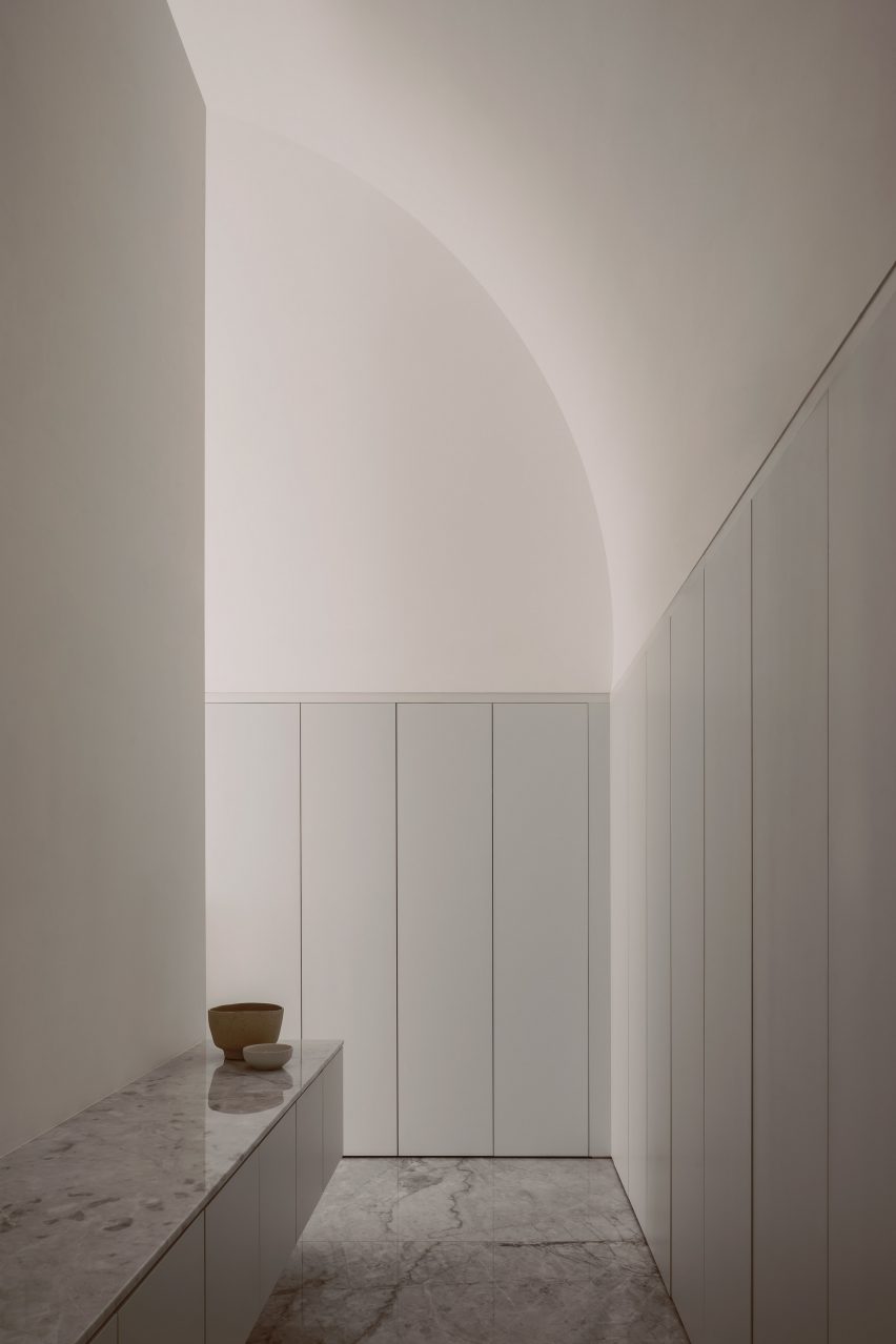 A white room with an arched ceiling and built-in wall cupboards