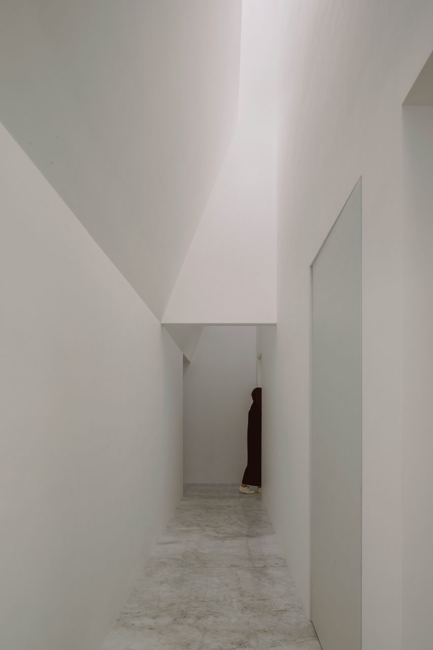 A white internal corridor with a skylight letting in sunlight