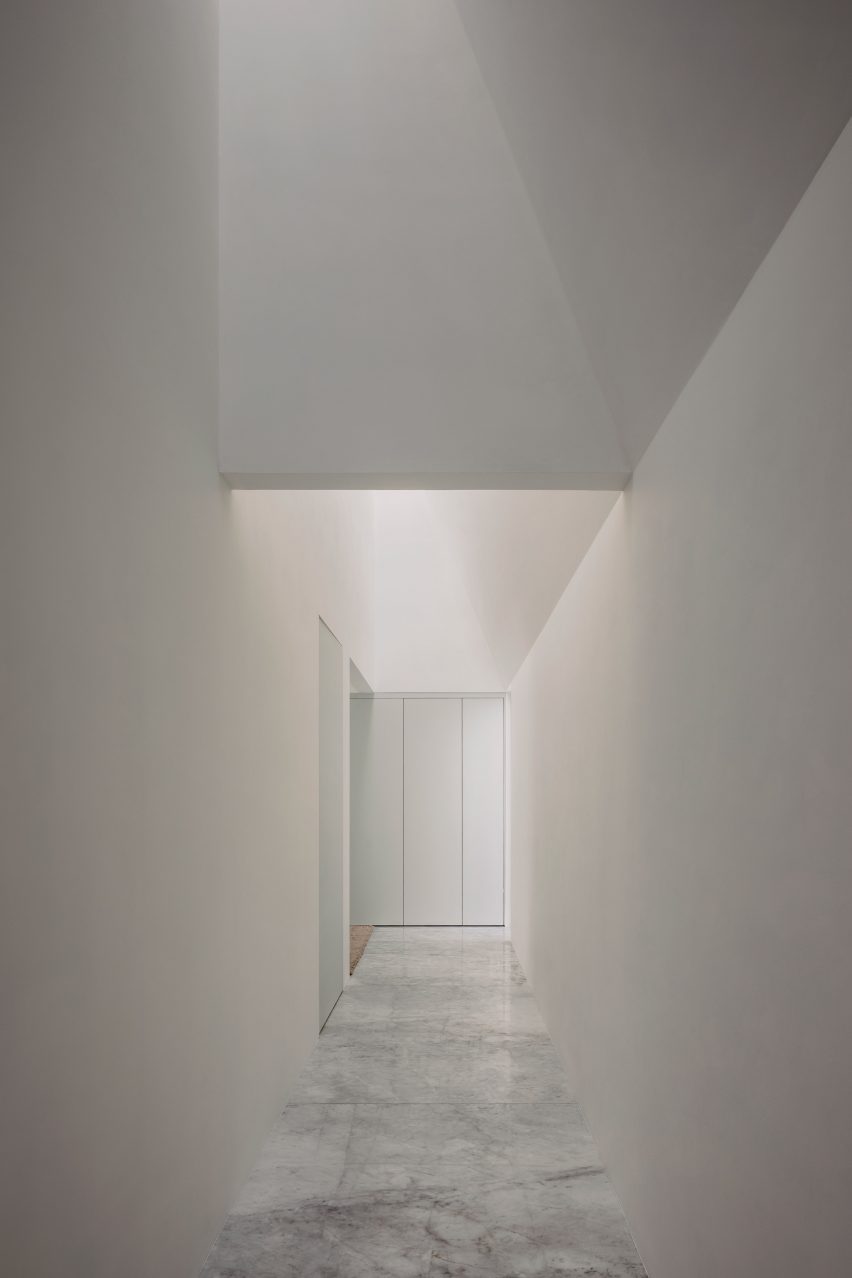 A white internal corridor with a skylight letting in sunlight
