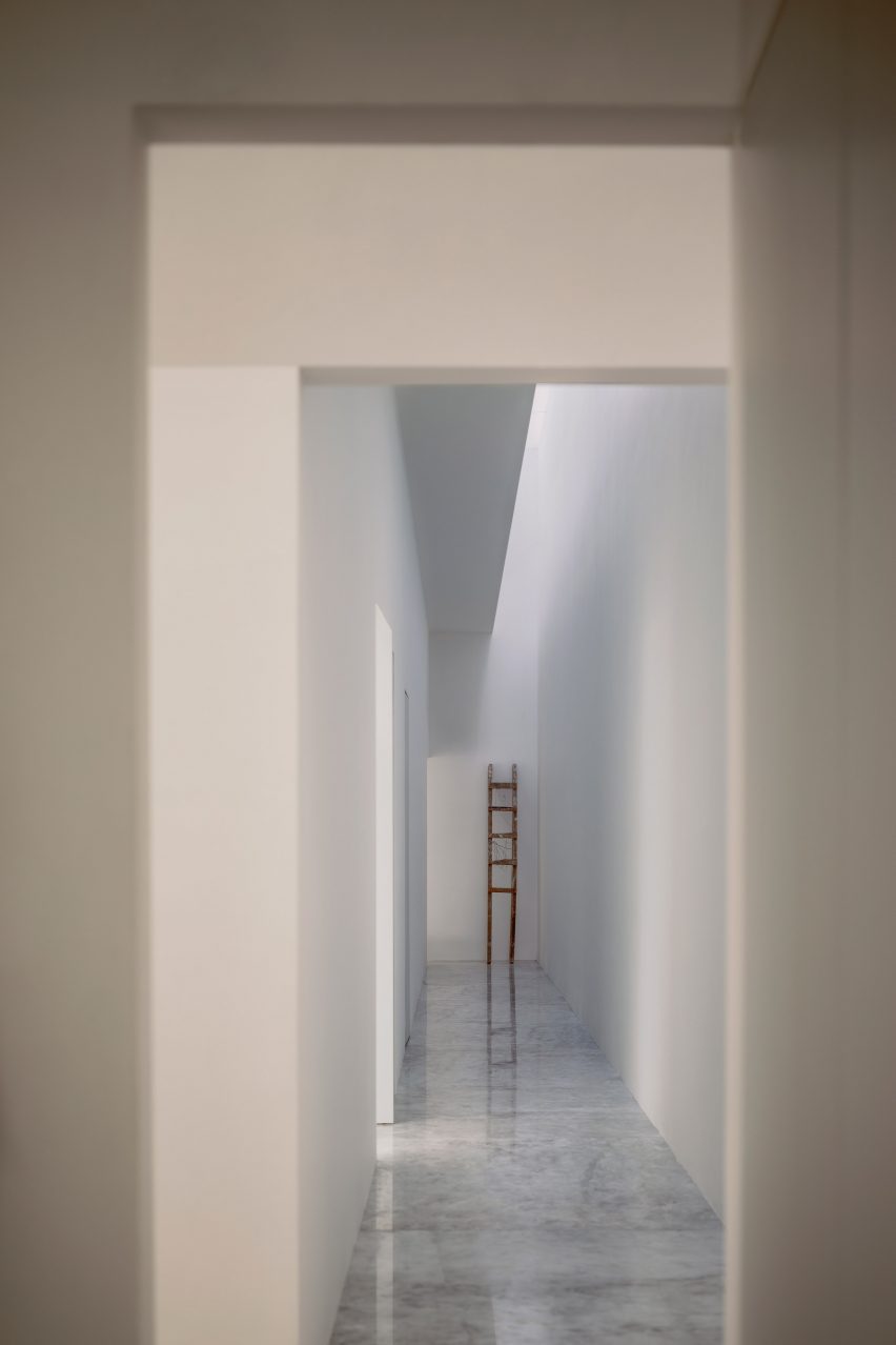 A white internal corridor with a skylight letting in sunlight
