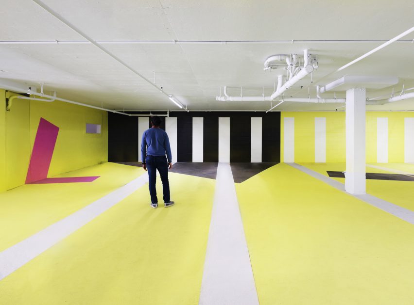 Large open venue space with a white, yellow and black graphic design on the walls and floor