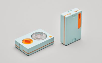 Photo of two pale blue-green flashlights shaped like decks of cards, one seen from the front and one from the back. The one facing the front has a large circular lamp with a bright orange dial beneath it