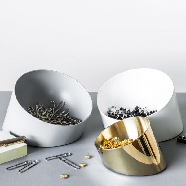 Slanted bowl containing paperclips and office supplies on table
