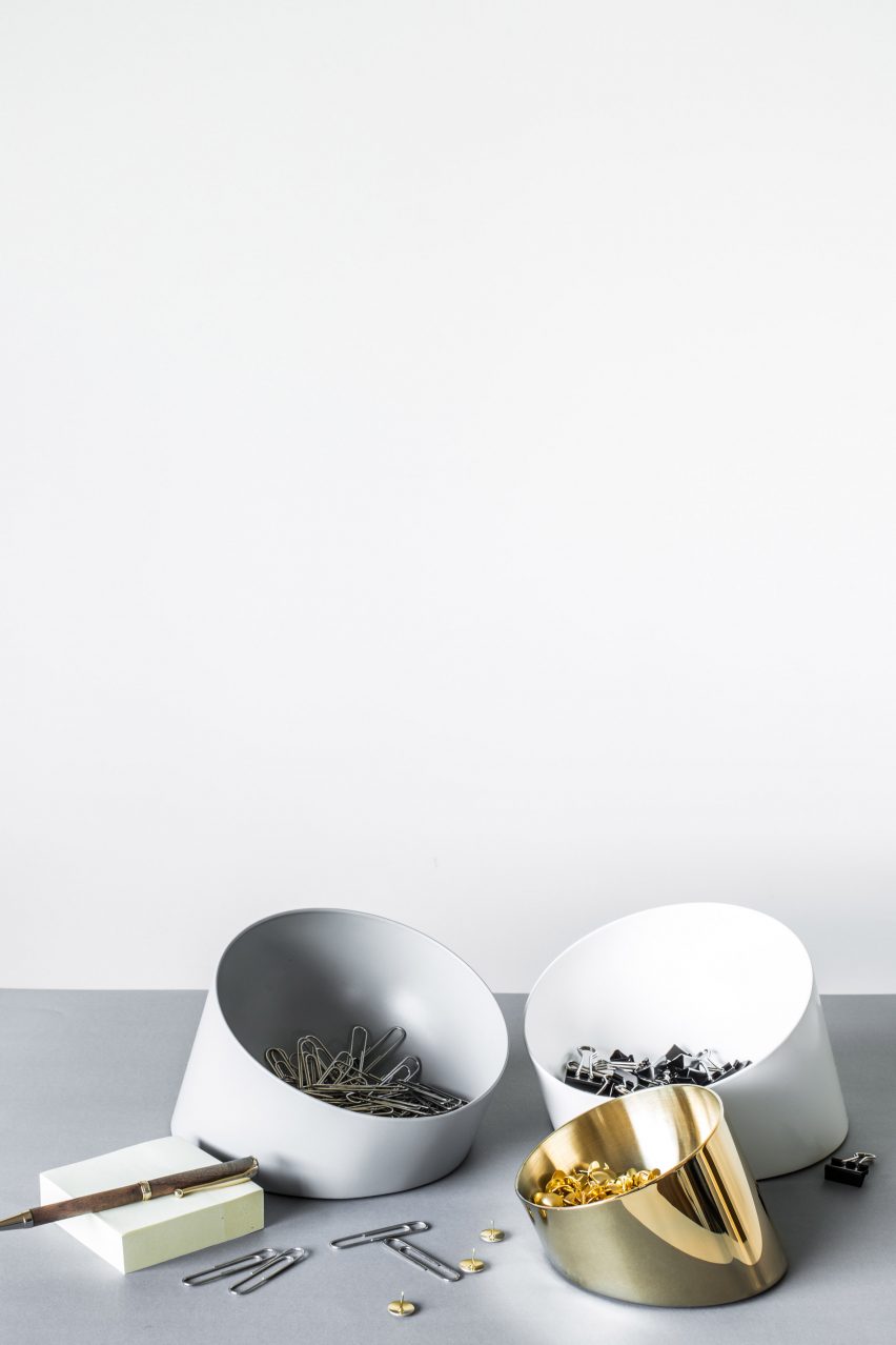 Slanted bowl containing paperclips and office supplies on table